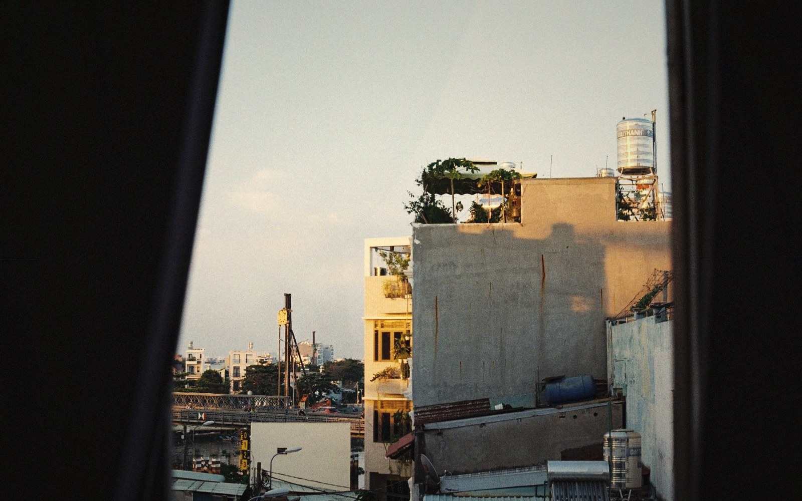 Rooftop garden and water tank atop a building, seen through a window frame